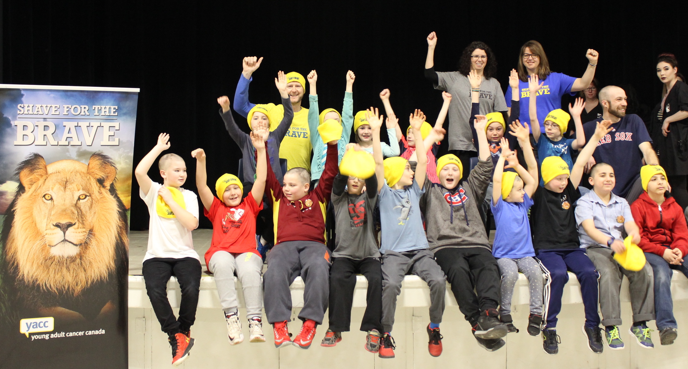 16 shavers posing with their arms raised after a successful shave!