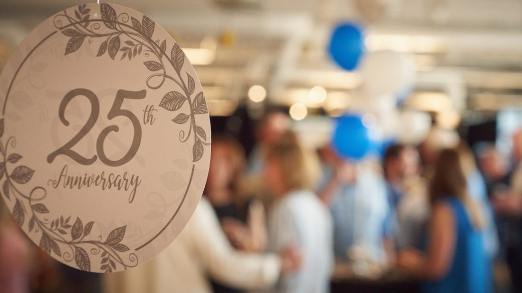 A close up image of a 25th birthday decoration with a blurry crowd in the background.