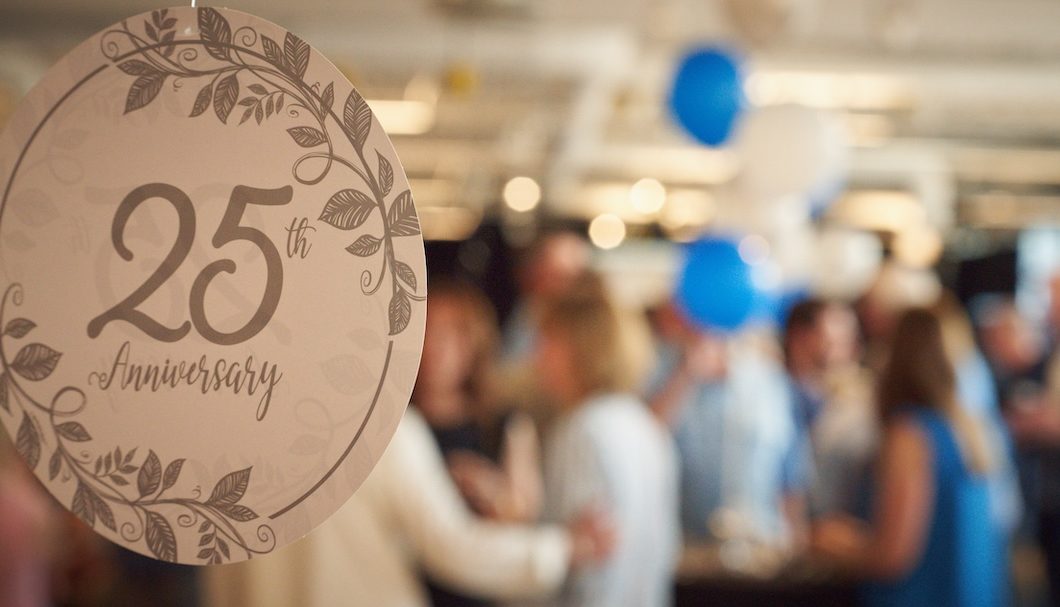 A close up image of a 25th birthday decoration with a blurry crowd in the background.