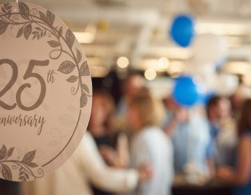 A close up image of a 25th birthday decoration with a blurry crowd in the background.
