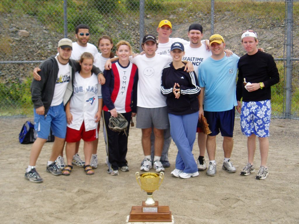 A softball team groups together behind the championship trophy. 