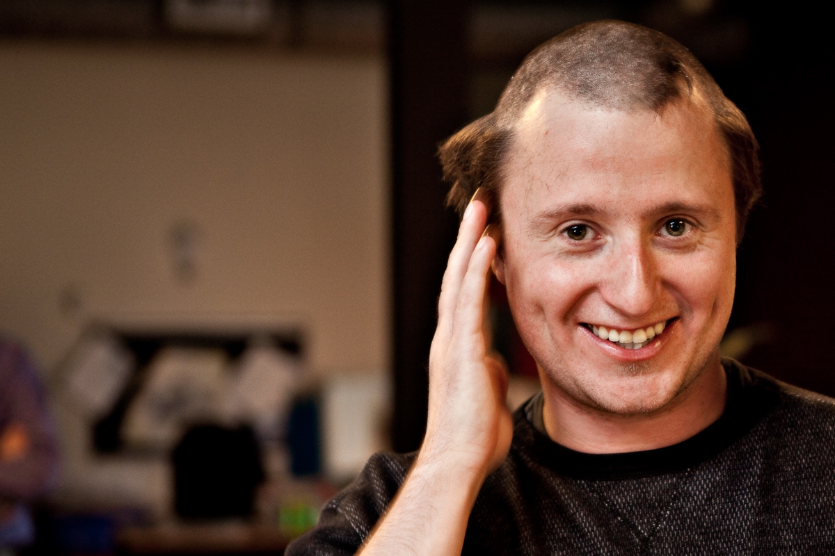 Gareth Milton with half his hair buzzed with a smile on his face