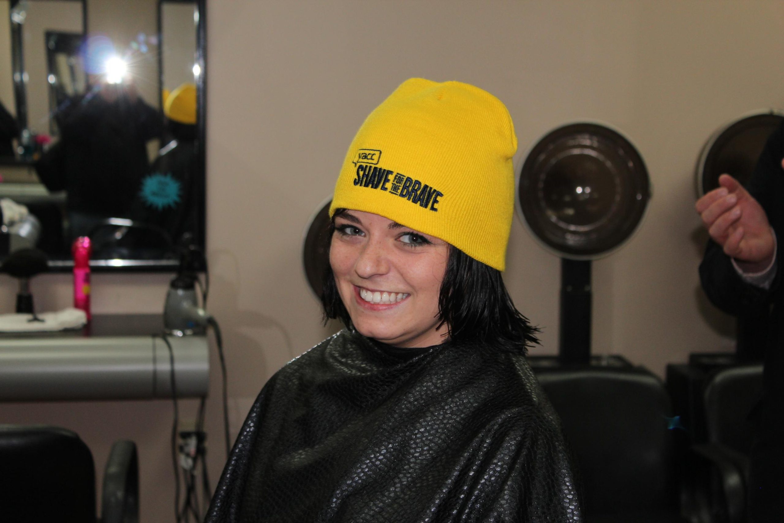 Thea smiling with her shave hat after cutting her hair