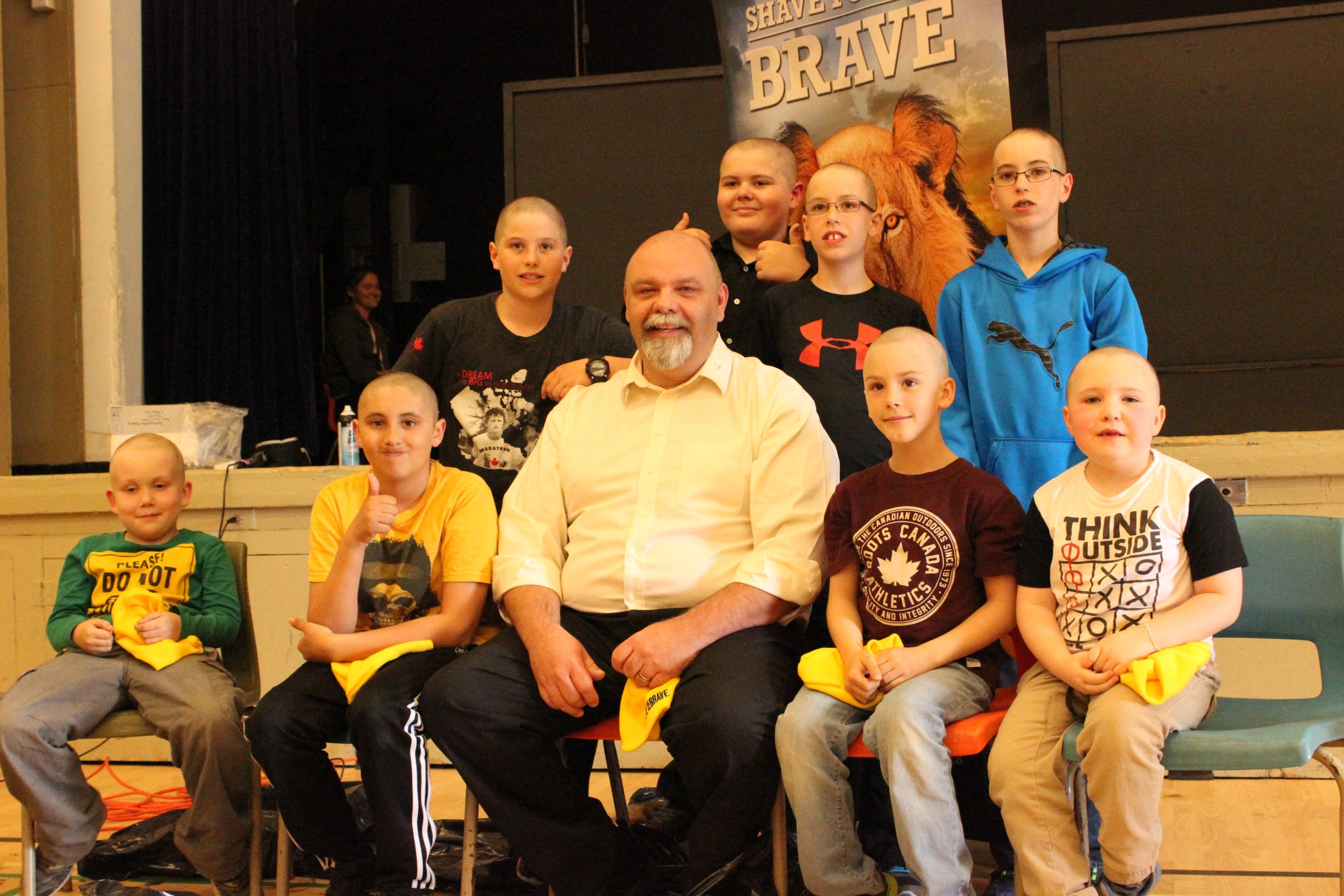 8 young shavers posing for a photo with their principal who also decided to shave his head for the brave.