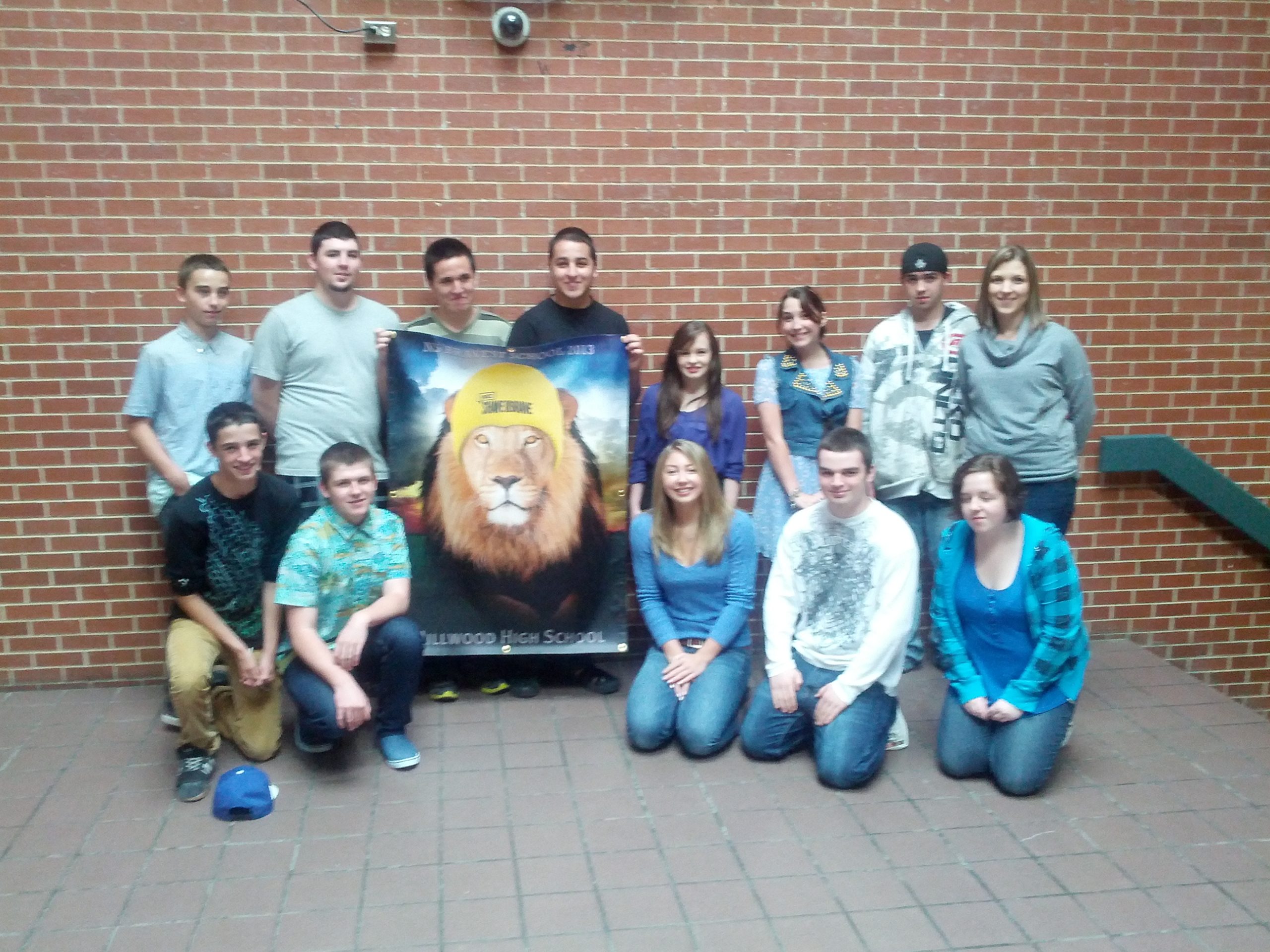 13 students posing with a Shave Banner
