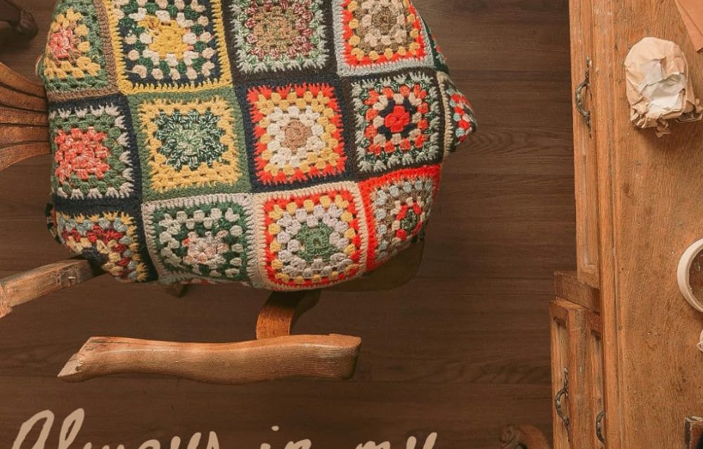 The cover image of "Always In My Heart," Angela Kater's book that Stephanie finished for her. It is an aerial shot of a desk and chair. There is a crocheted blanket on the seat of the chair.
