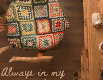 The cover image of "Always In My Heart," Angela Kater's book that Stephanie finished for her. It is an aerial shot of a desk and chair. There is a crocheted blanket on the seat of the chair.