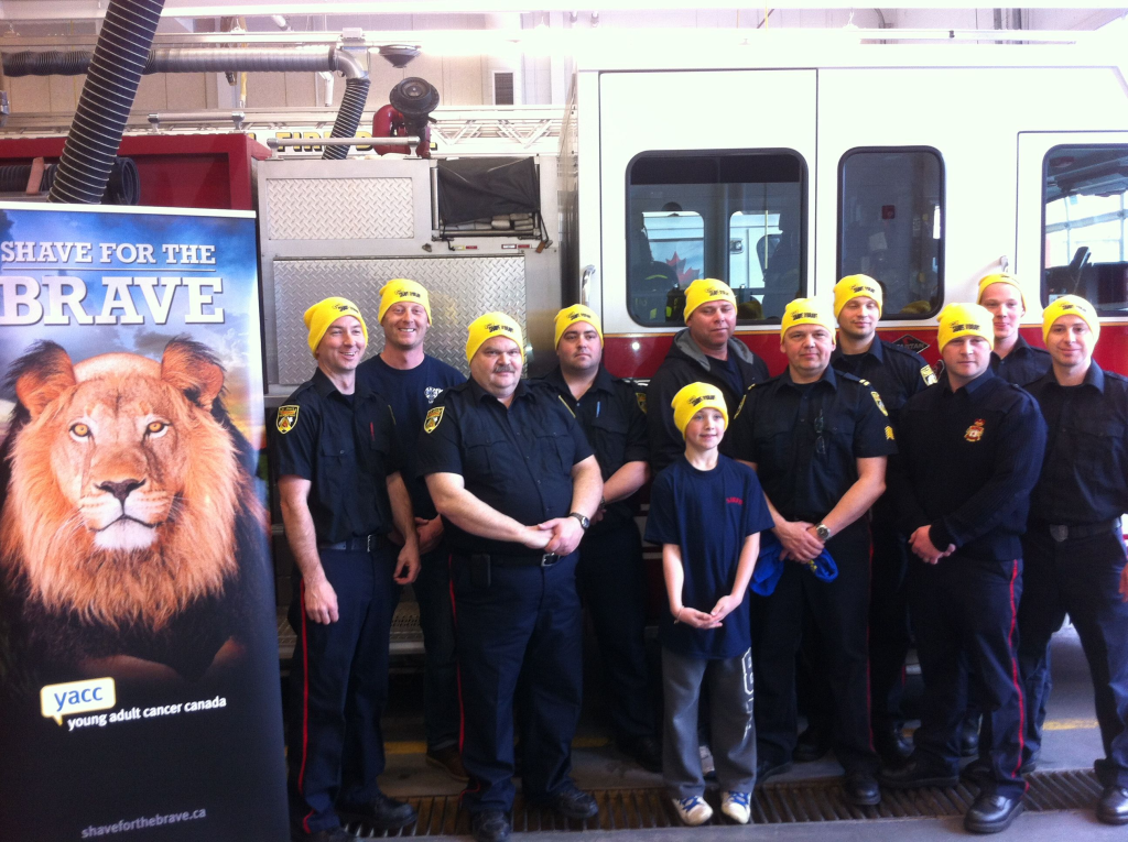 A group of firefighters poses together by a fire truck in their Shave toques.