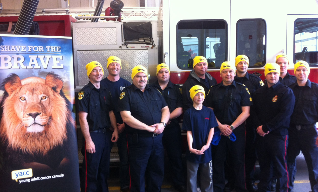A group of firefighters poses together by a fire truck in their Shave toques.