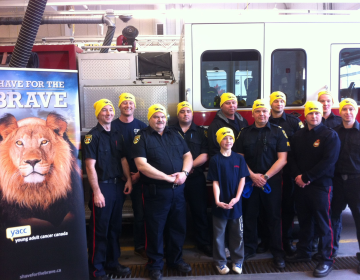 A group of firefighters poses together by a fire truck in their Shave toques.